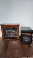 Photo of the electric fireplace and EdenPURE heater side by side on hardwood floor against white wall.