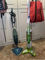 Full view of Hoover steam mop and Bissell vacuum standing side by side showing overall condition and colors