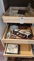 Drawer with mason jars, covered dish, cheeseboard set with wooden paddles, salt and pepper shakers, and books