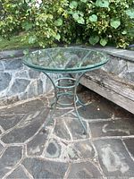 Full view of round patio table with glass top, showing metal frame and condition.