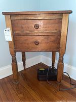 Front view of the wooden table with two drawers, showing the turned legs and wooden knobs.