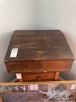 Front view of wooden writing desk with slant lid closed showing overall wood grain and surface condition.
