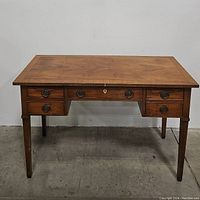 Front view of solid wooden writing desk showing five drawers and metal round drawer handles