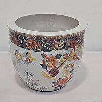Full view of the white ceramic planter pot with colorful Asian floral design and decorative border near the rim