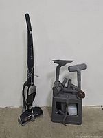 The Electrolux cordless stick vacuum standing next to the charging base with several vacuum cleaning attachments organized.