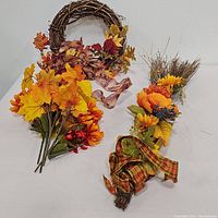 Full lot display showing the grapevine wreath and loose fall flowers on the left, and the fall door hanger on the right.