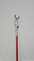 Long-handled tree trimmer with red and silver extendable pole and cutting head.
