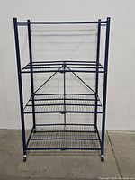 Front view of the blue 4-shelf metal storage rack showing its foldable design and wire grid shelves.