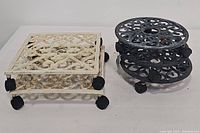 Photo showing two cream-colored square plant caddies and three stacked round black caddies, illustrating both styles and colors included in lot.