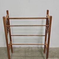 Front view of the wooden quilt rack showing its four horizontal bars and overall structure.