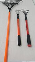 Three garden rakes laid flat showing full length and detailing grips and tines
