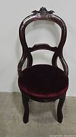 Front view of Victorian occasional chair showing hand carved back and velvet seat.