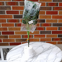 Full view of the Monstera artificial plant in the ceramic planter on marble table against brick wall