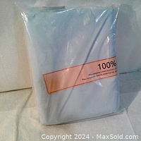 Photo showing baby blue cotton fabric neatly folded and packaged in clear plastic with label indicating 100% cotton content.