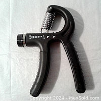 Image of hand grip strengthener showing full device with black ergonomic grip, steel spring, and resistance dial.