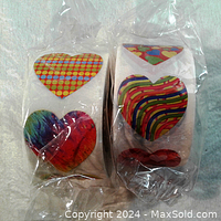 Two individual rolls of heart-shaped stickers featuring colorful and patterned hearts seen through clear packaging on a light background.