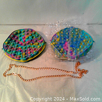 Photo showing both pop-it purses and the gold tone chains, highlighting the round and seashell shapes with colorful bubbles.