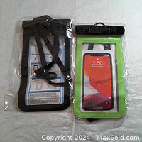 Two waterproof phone cases, one black bordered and one green bordered, fully sealed in clear plastic packaging, shown together