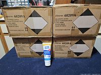 Four cardboard cases labeled Item No. 60209A stacked with one tube in front