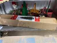 Full view showing boxed 3ft artificial Christmas tree with several colorful woven baskets behind it