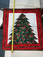 Red, white, and green quilted fabric with Christmas tree design and holly, candy canes, and ribbon motifs.