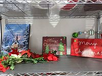 Christmas-themed wooden wall hangings and faux poinsettia flowers on metal shelving unit