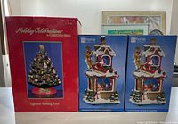 Photo showing boxed Holiday Celebrations lighted Christmas tree by Christopher Radko and two boxed musical Santa double snow globes from JC Penny Home Collection.