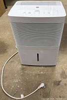 Front view of white GE dehumidifier showing vent slats and power cord on concrete floor.