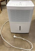 Front view of white GE dehumidifier with power cord laid out in front.