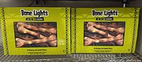 Two unopened boxes labeled 'Bone Lights' containing 10 glowing and touchable bone decorations each with LED lighting, in Halloween color packaging.