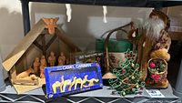 Photo showing wooden nativity stable with clay figures, boxed olive wood camel caravan, vintage Santa Claus figure and Christmas tree candle holder.