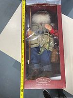 Large Fisherman Santa figure in original box, about 16-17 inches tall, wearing fishing vest and holding fishing rod.
