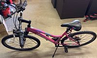 Full side view of pink Schwinn High Timber bicycle showing 26-inch frame and tires, black seat, and attached kickstand