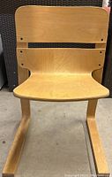 Front view of one light wooden bent plywood chair showing curved seat and backrest with visible screws.