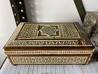 Ornate wooden jewelry box with detailed geometric inlay on the lid and sides.