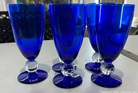 Photo showing 6 of the blue juice glasses with clear round stems and blue bases.