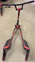 Front perspective view of the red and black Yvolution Fliker Lift Drift scooter showing the handlebar, foot platforms, and wheels on concrete floor.