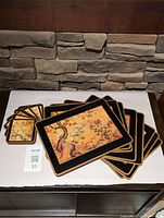Eight Asian motif placemats and six matching glass coasters arranged on table.