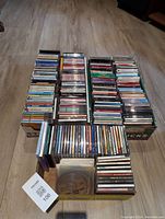 Four stacks of around 100 CDs in cases and paper sleeves, mostly classical and brass music.
