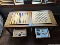 Full overhead view of pine game table with two reversible panels: backgammon on left, chess/checkers on right. Both drawers open showing game pieces inside.