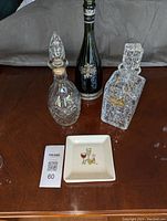 Photo showing two decanters and decorative bottle alongside one square ceramic plate with colorful cocktail graphic.