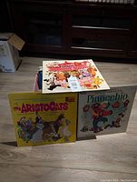 12 children's vinyl LP records in a red box, showing titles including Disney's The Aristocats, Pinocchio, and others.