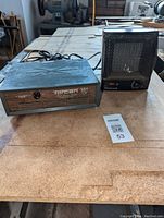 Front view of Totcan 769 space heater and Honeywell space heater on wooden surface with item tag.