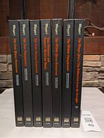 Seven black boxed sets with titles and Mozart's image on spines, standing vertically.