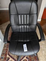 Front view of black vinyl office chair showing seat, backrest, and armrests.