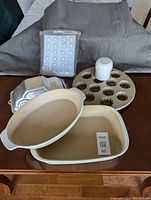 Overview of Pampered Chef stoneware baking dishes, cupcake mold, car cake pan, heart chocolate molds and vegetable slicer on table