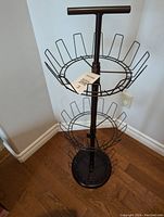 Full view of 3-tier metal revolving shoe rack standing on hardwood floor, showing circular wire racks and base.
