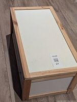 Top view of rectangular wooden toy box with white panel and natural wood frame