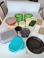Front view of assorted plastic storage containers in various shapes, sizes, and colors including green, red, cream, black, and turquoise colors.