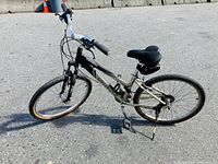 Side view of black and beige Specialized Expedition Deluxe bicycle showing frame, tires, seat and handlebars.